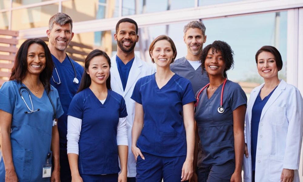 Smiling medical team standing together outside a hospital